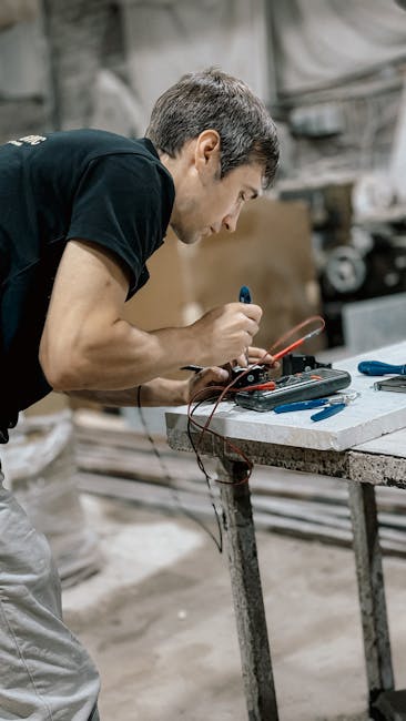 Engineer testing equipment with multimeter in a workshop environment, focused on precision.
